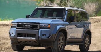 a blue car parked on dirt near water